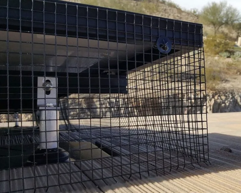 Close-up of black PVC-coated steel bird guard mesh clipped to the frame of a rooftop solar panel