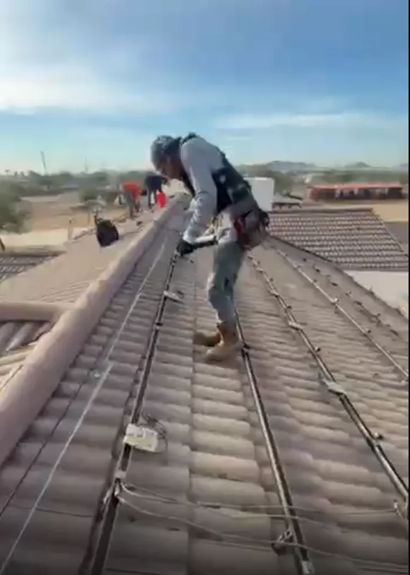 Technician measuring solar system output with a clamp meter at the electrical panel