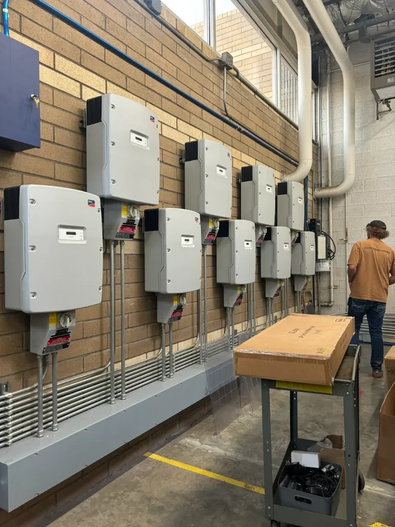 Bank of SMA solar inverters mounted on a commercial wall with conduit runs, serviced by Solar Detach and Reset
