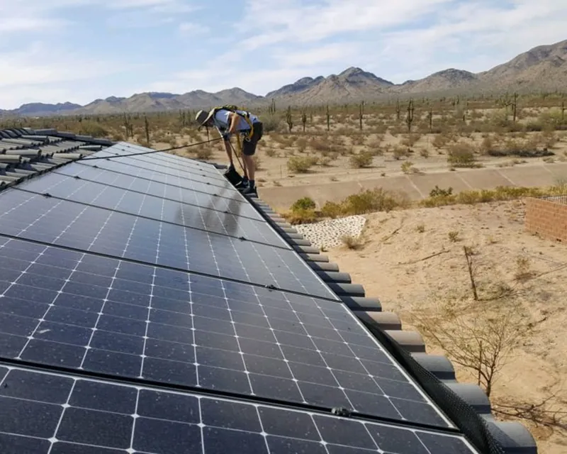 Technician on a residential solar array in the Arizona desert verifying system performance