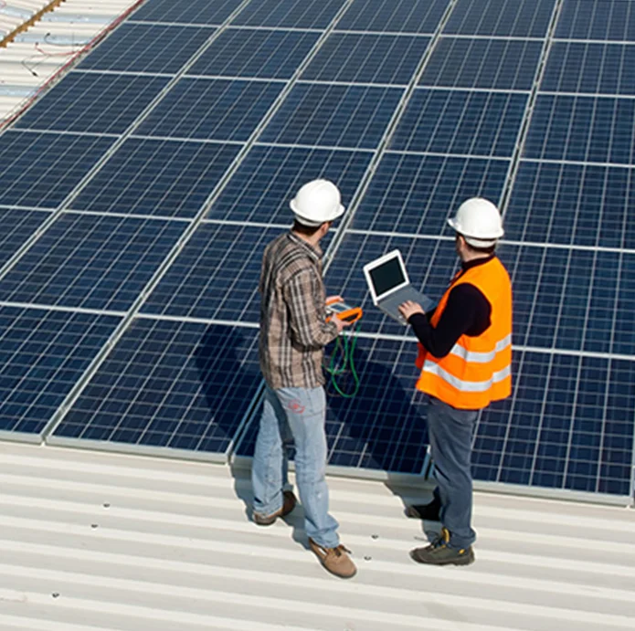 Workers inspecting solar panels on a rooftop, utilizing a laptop and measuring device, highlighting innovation in sustainable energy solutions.