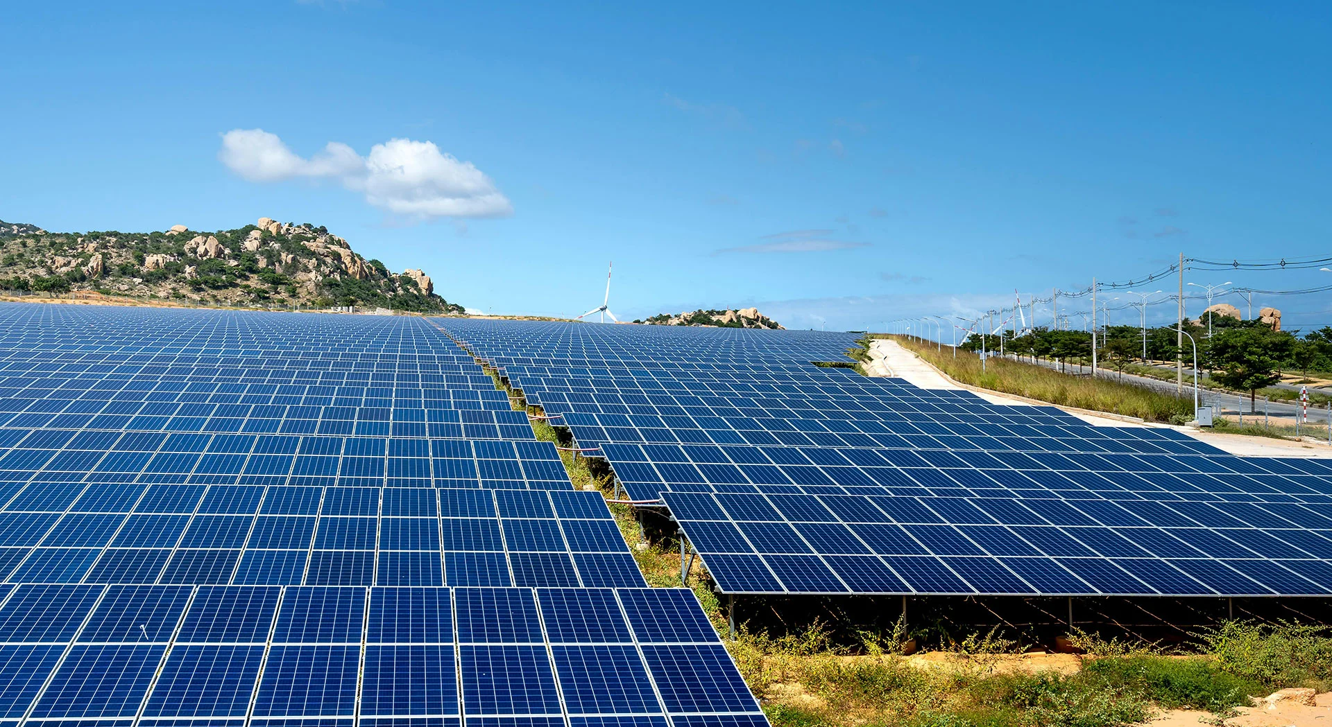 Solar panel array in Arizona, showcasing solar energy solutions and sustainable infrastructure, with mountains and wind turbines in the background.