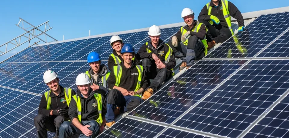 Team of solar panel installers on a rooftop, showcasing solar technology and sustainable energy solutions.