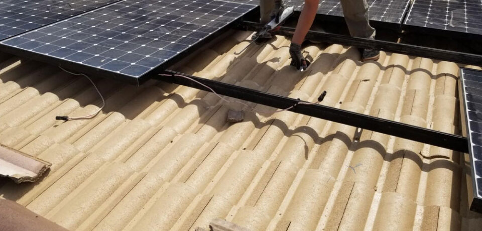 Solar panel installation on a textured rooftop, showcasing a technician handling equipment for the licensed solar detach and reset service in Arizona.