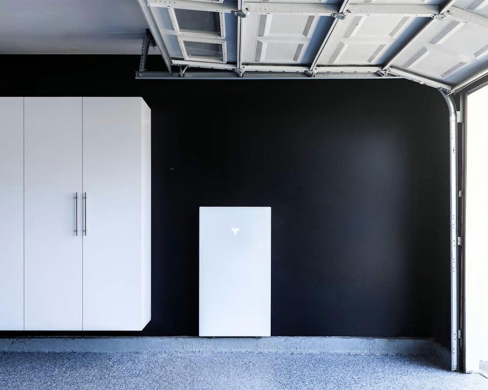 Tesla Powerwall 3 battery system installed in a modern garage with black walls and white cabinetry, showcasing energy storage solutions for Arizona homeowners.